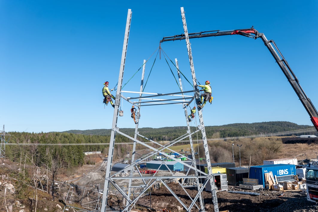 Bilde av fire personer som klatrer i høyspentmast.