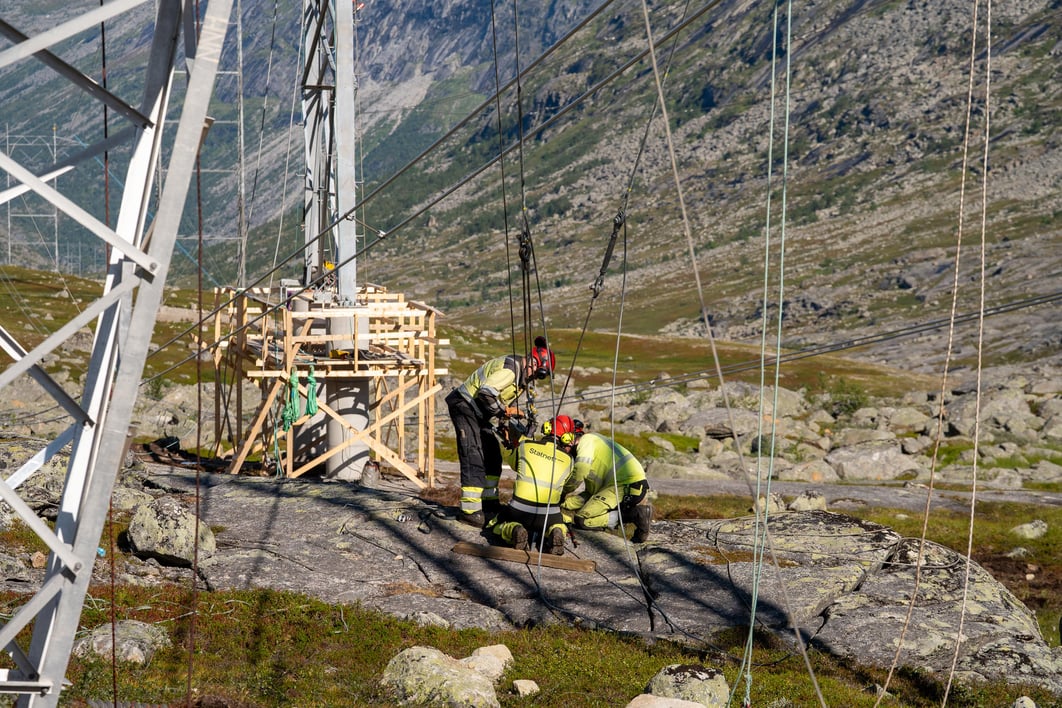 Tre personer som samarbeider på en mast.