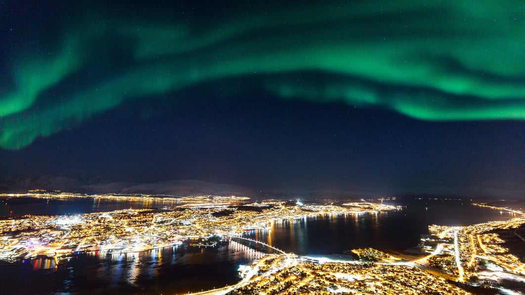 Tromsø by med Nordlys på himmelen.