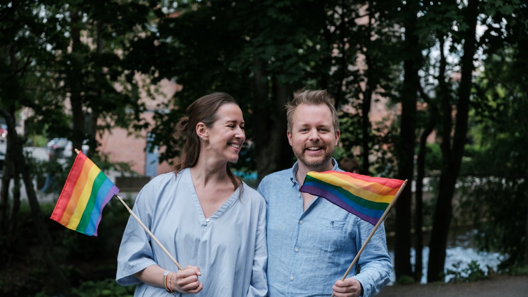 To mennesker som holder hvert sitt pride-flagg.