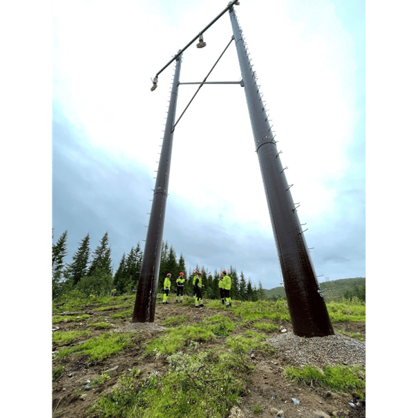 Stor svart mast med ansatte i vernetøy under masten 