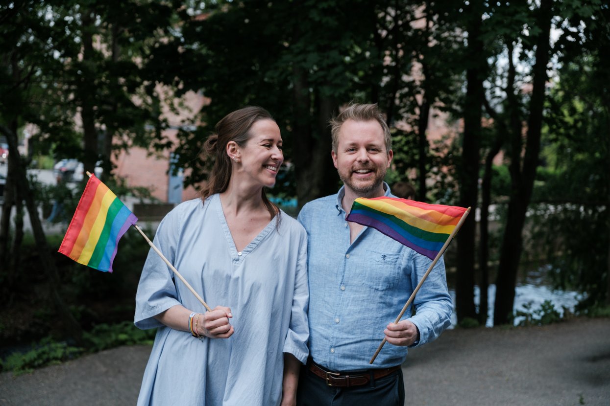 To mennesker som holder hvert sitt pride-flagg.