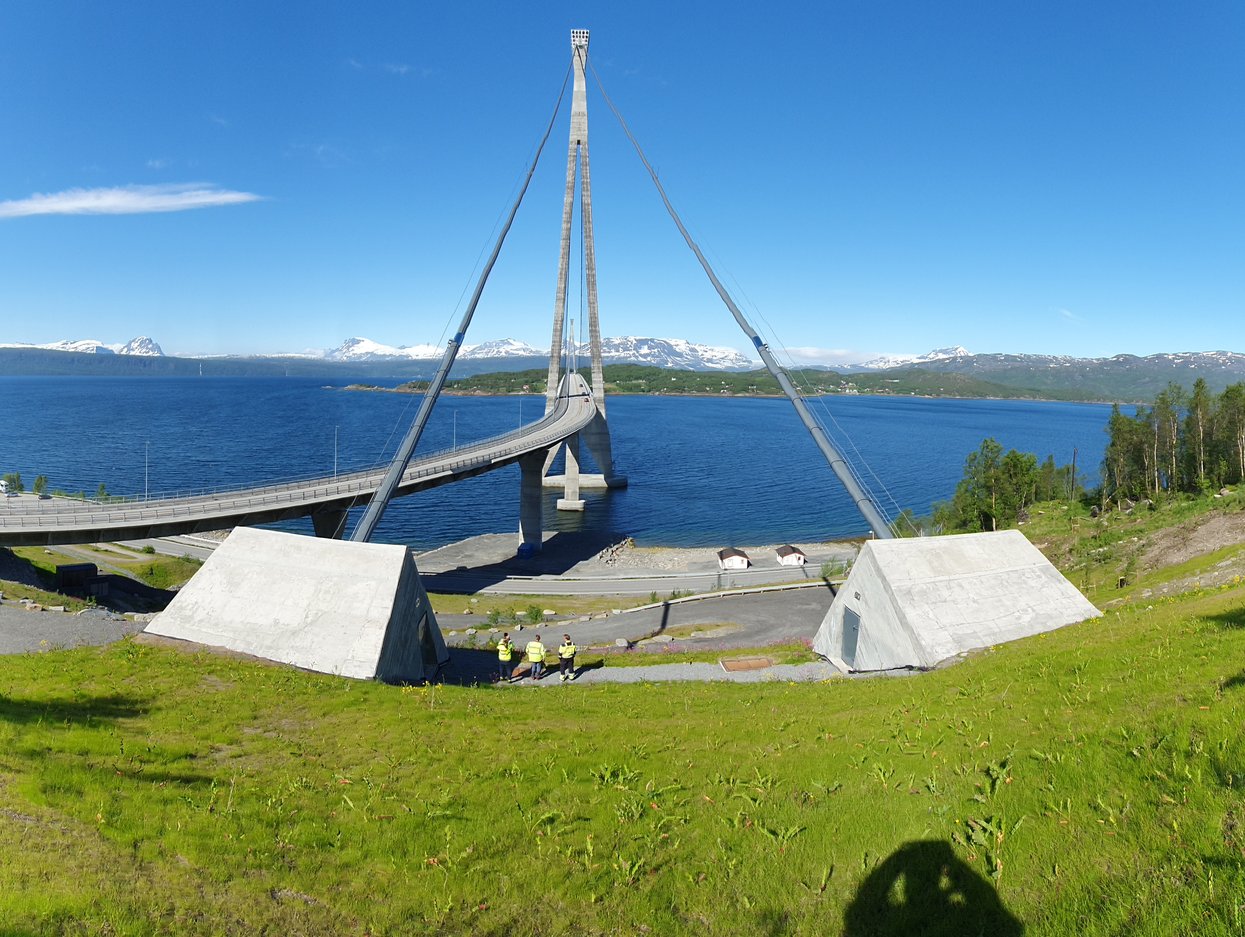 Bro i havet med fjell med snø rundt. 