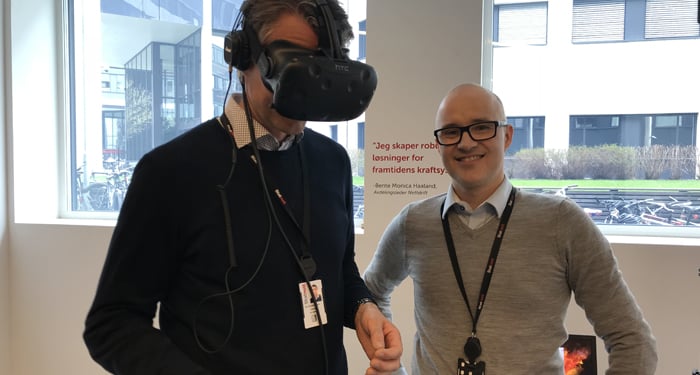 Man using VR glasses while a colleague stands beside him indoors