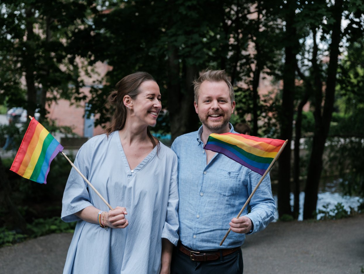 To mennesker som holder hvert sitt pride-flagg.