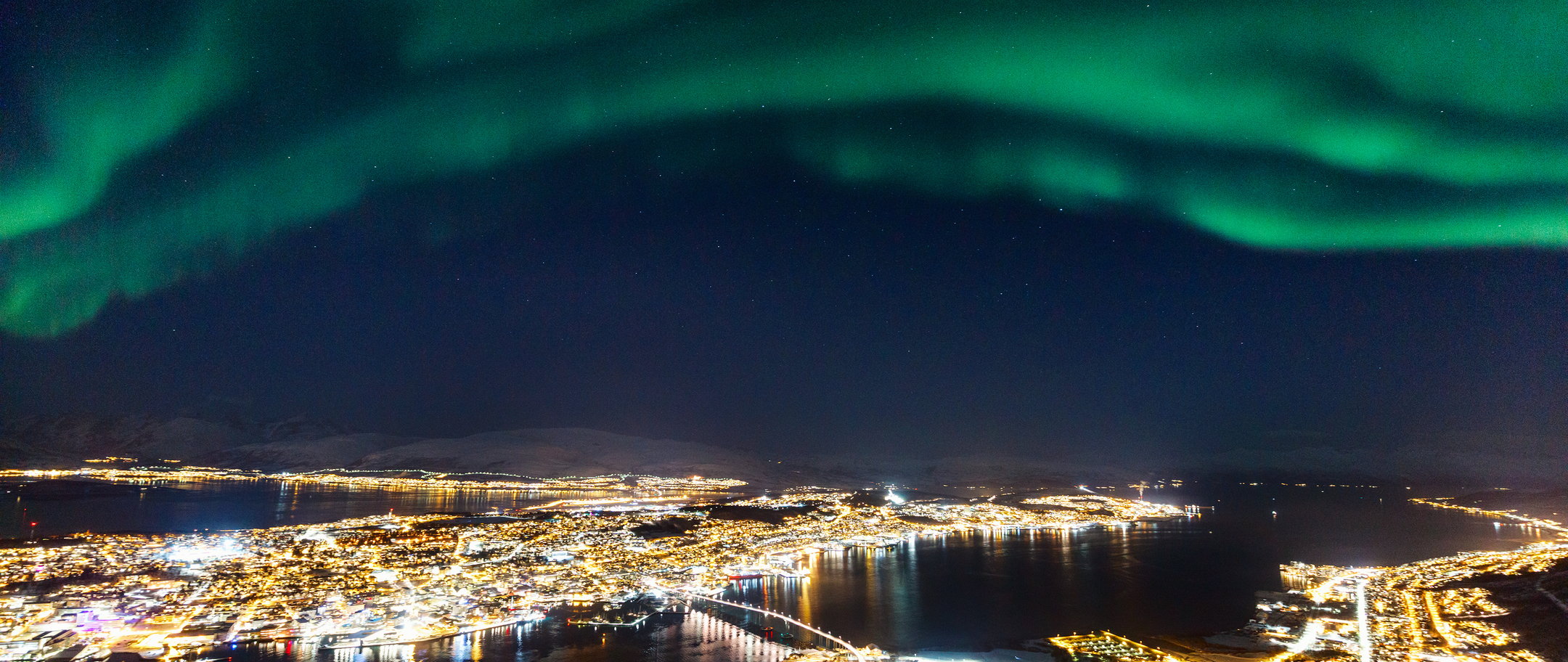 Tromsø by med Nordlys på himmelen.