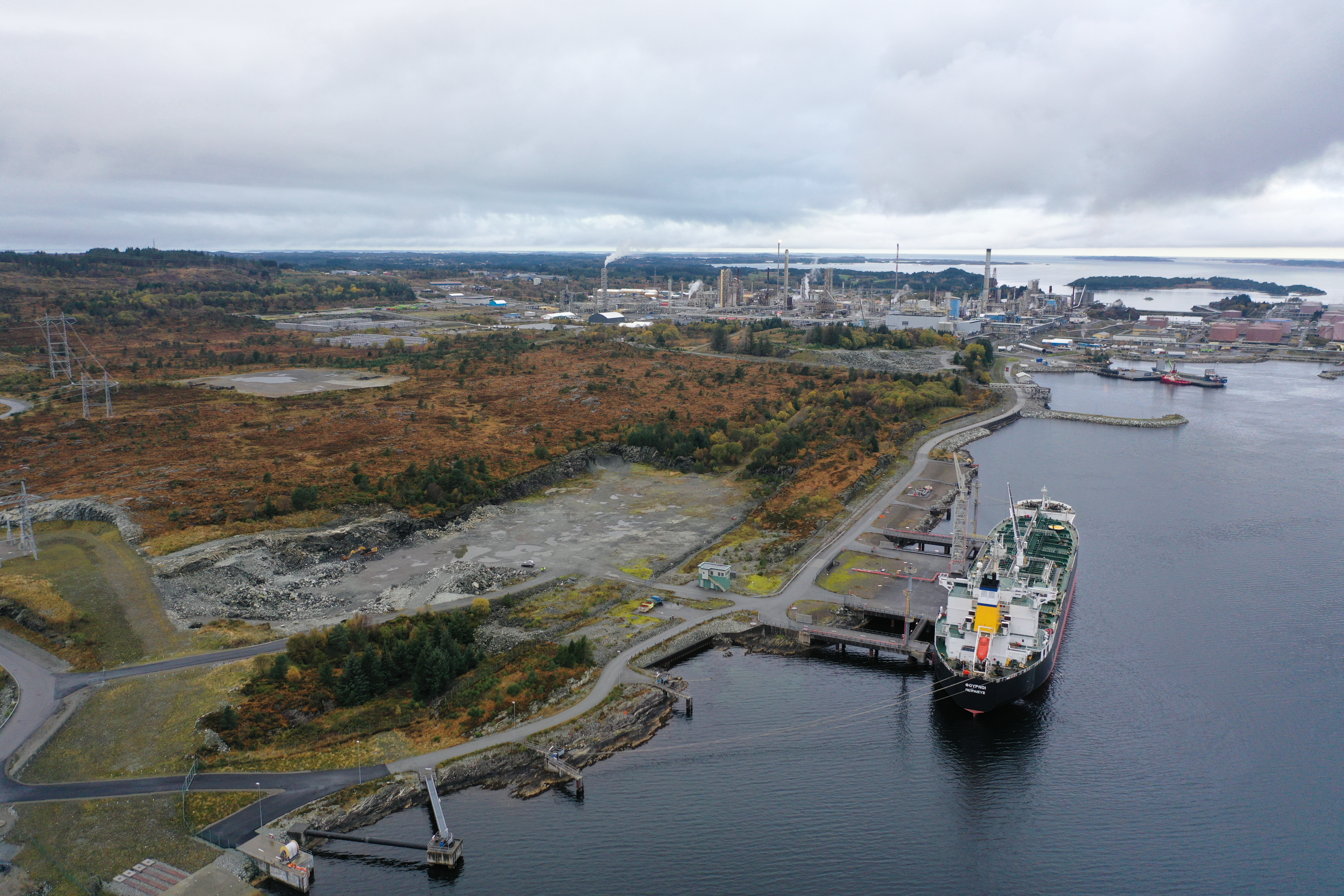 De ledige tomtearealene sør for raffineriet på Mongstad skal brukes til ny grønn industri. Utfordringen er kapasitet i strømnettet. Nå går Statnett og BKK sammen om å finne nye innovative løsninger for å øke kapasiteten i industriområder som Mongstad og Kollsnes.  Foto: Screen Story/BKK