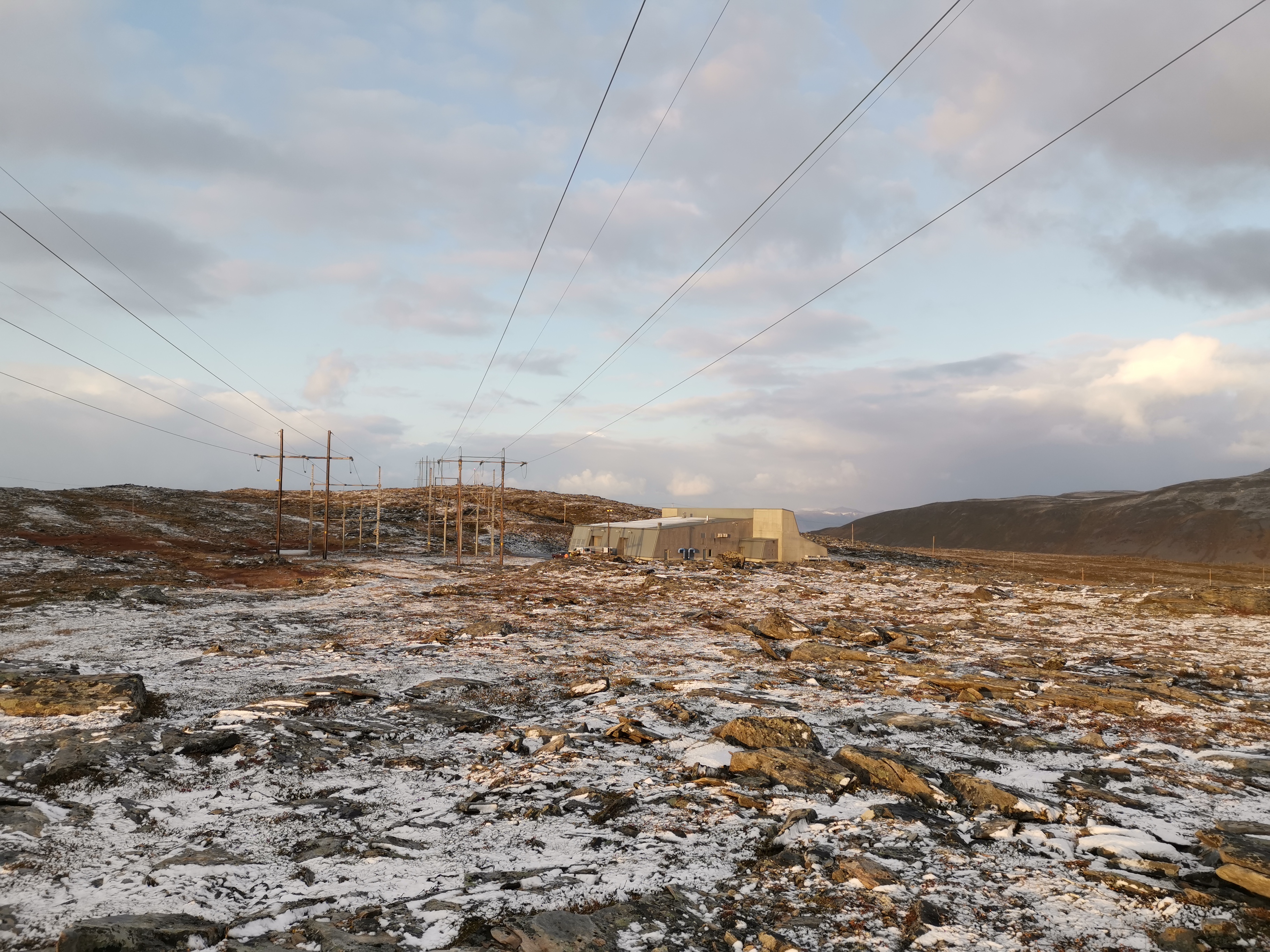 To kraftledninger og trafostasjon med litt snø på bakken 