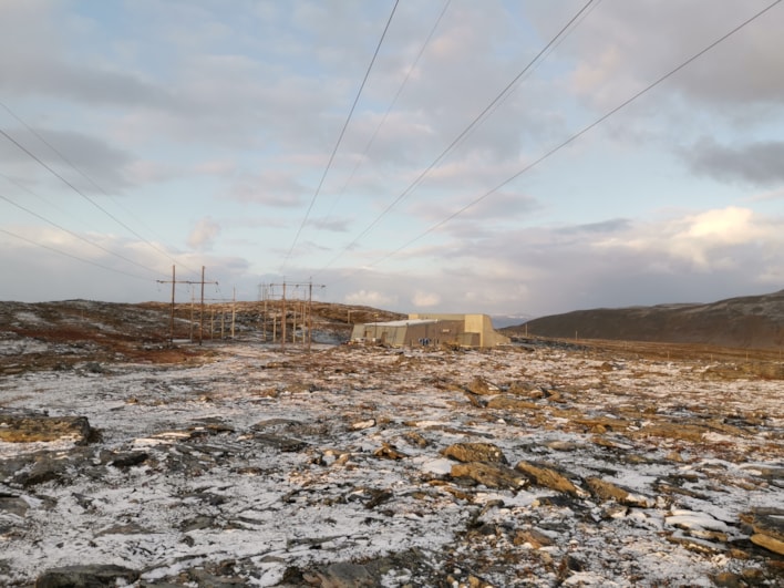 To kraftledninger og trafostasjon med litt snø på bakken 