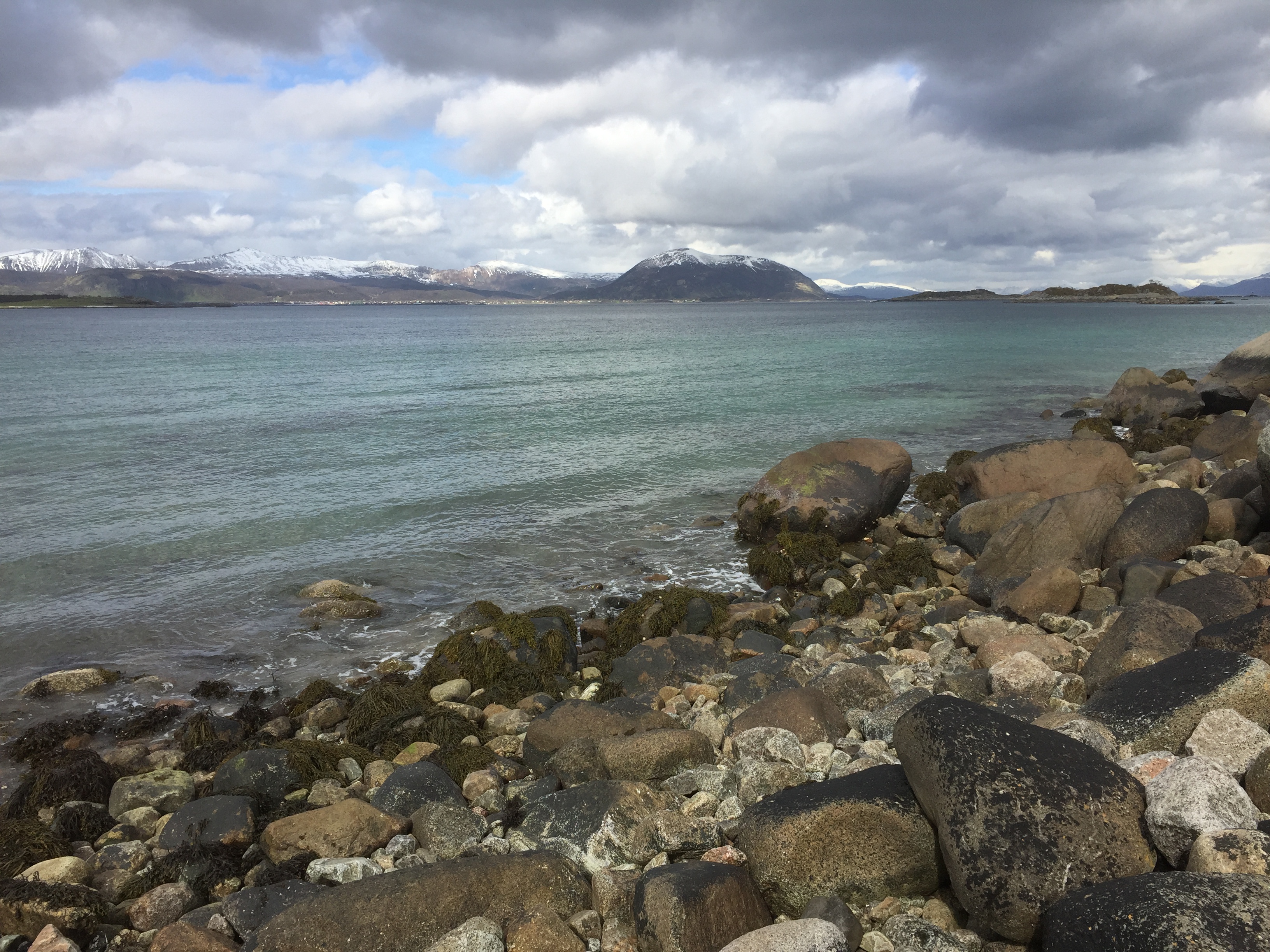 Mange store steiner langs vannkanten og store grå skyer