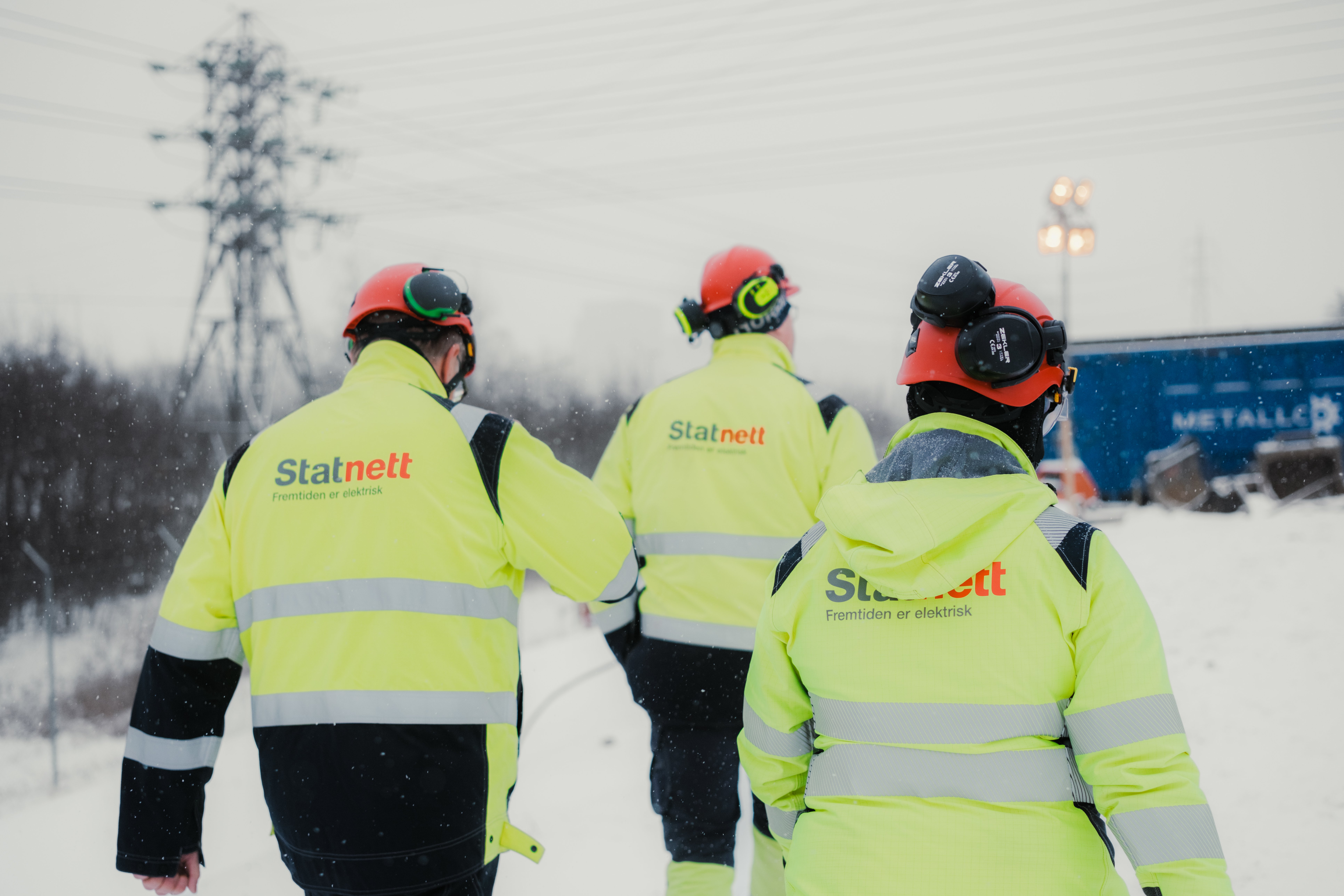 Picture of three people with their backs turned, wearing protective clothing