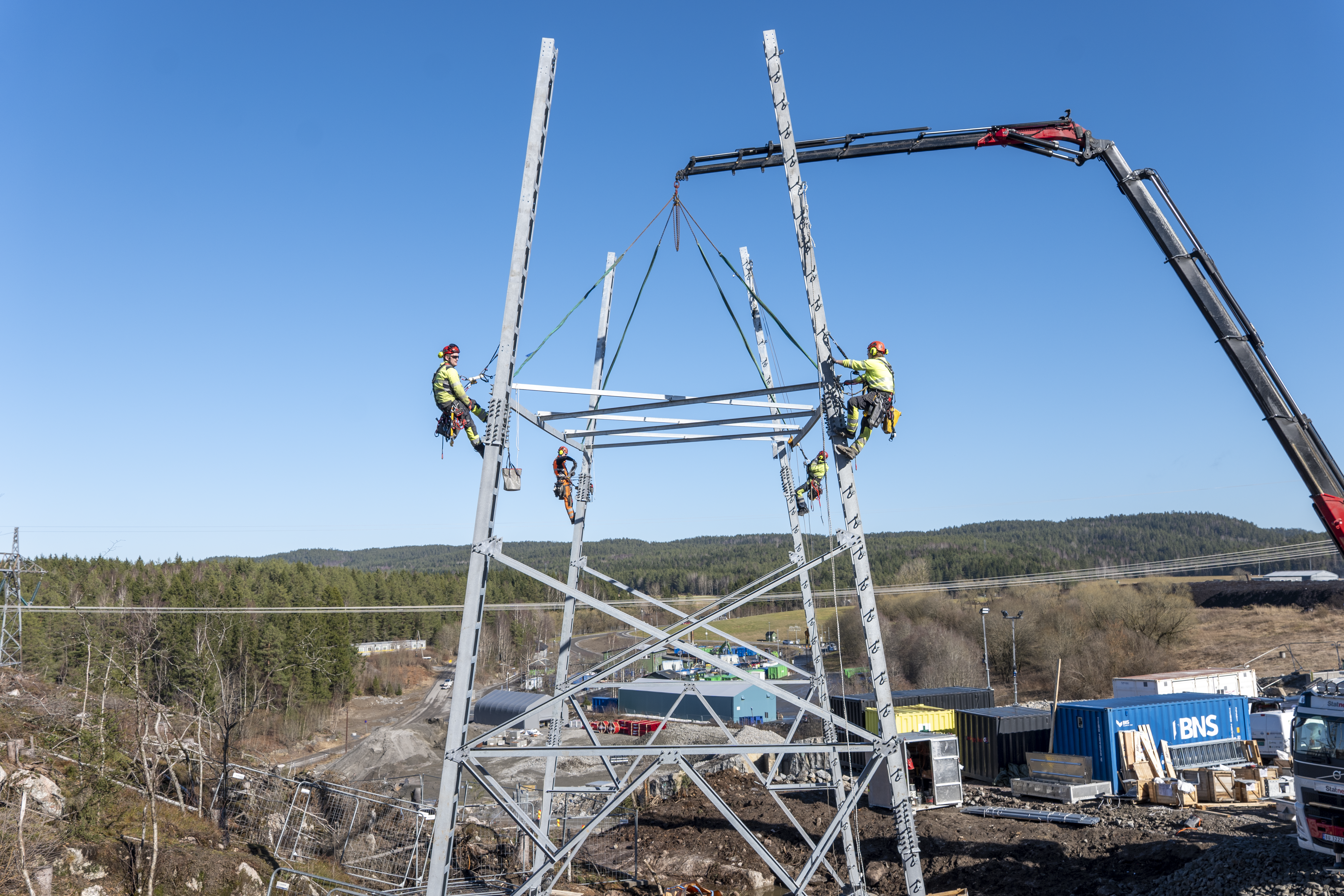 Bilde av fire personer som klatrer i høyspentmast.