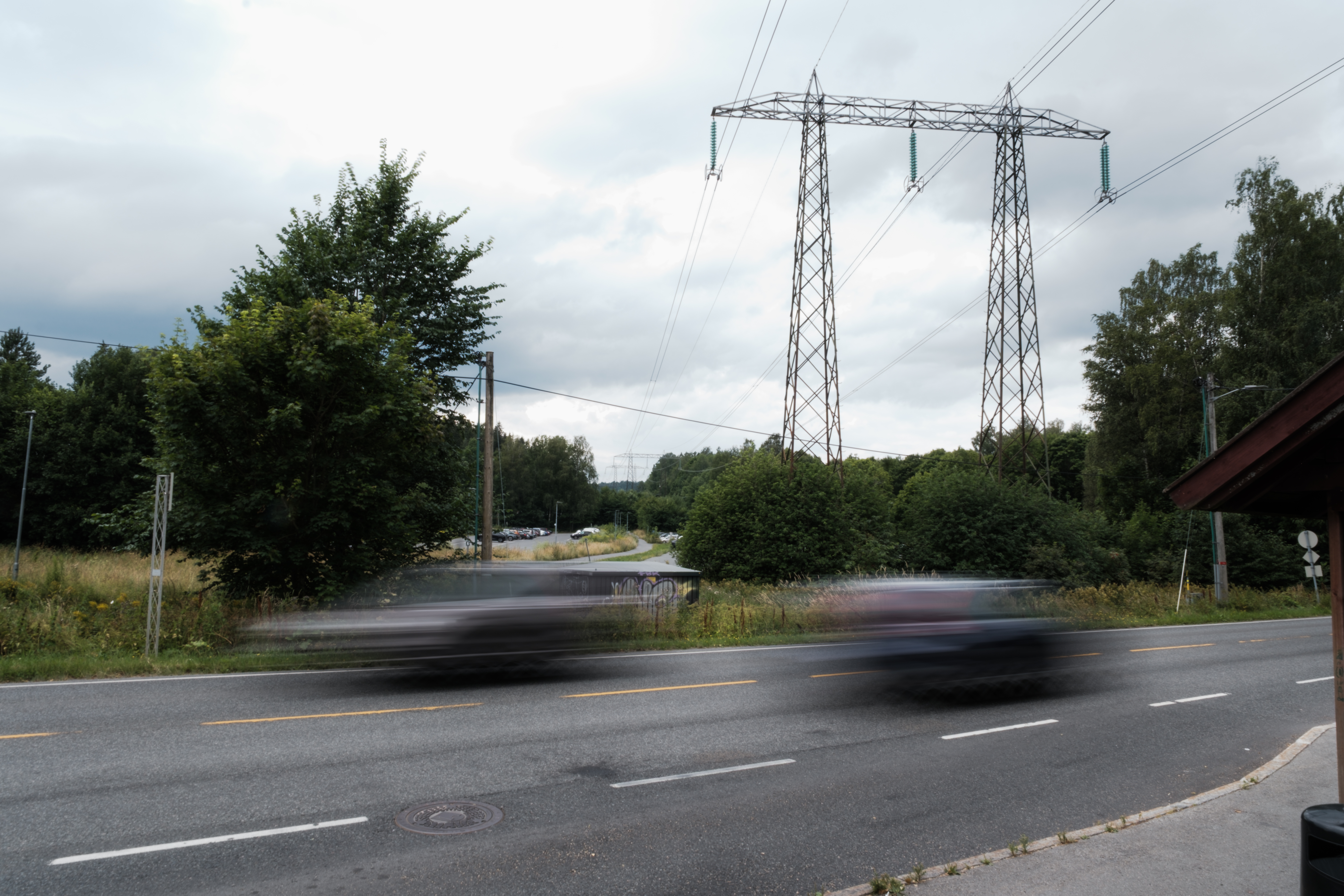 Bilde av en høyspentmast og biler som kjører forbi 