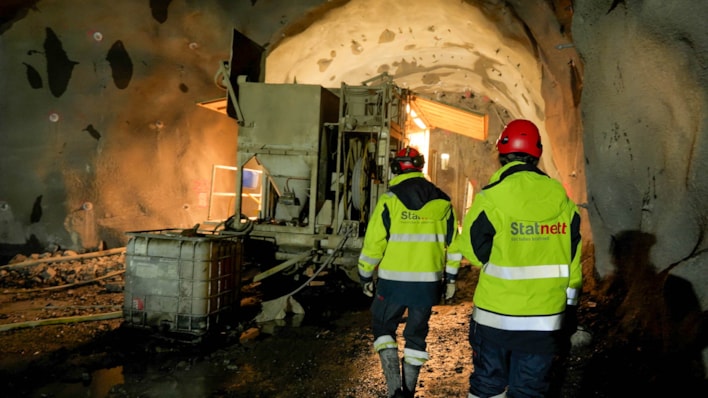 Bilde av tunnel, maskin og to personer bakfra
