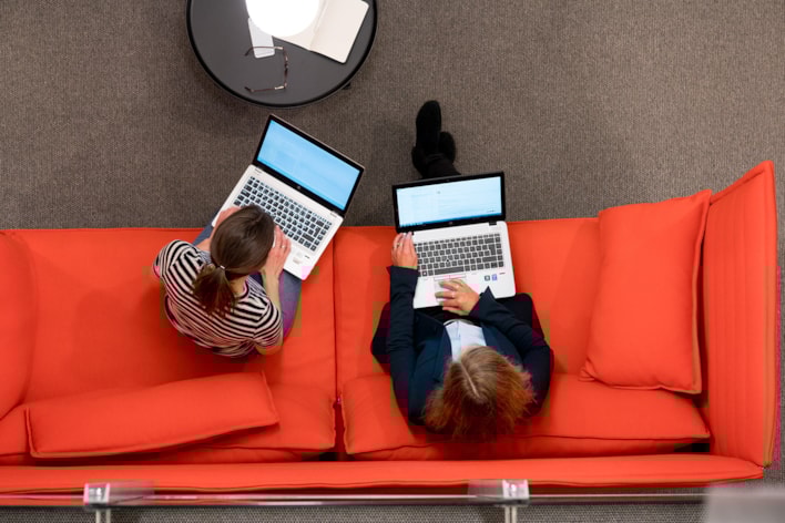 Kollegaer som sitter i sofa og jobber på pc'ene sine
